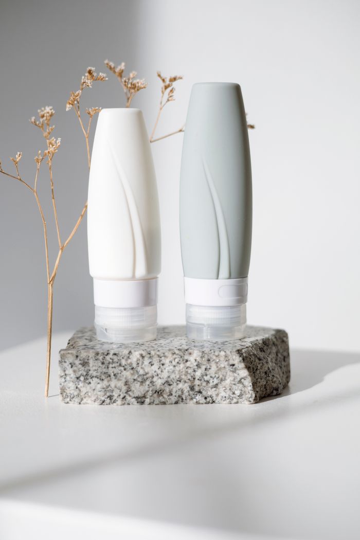 Minimalist skincare product mockup featuring two elegant tubes on stone with natural lighting.